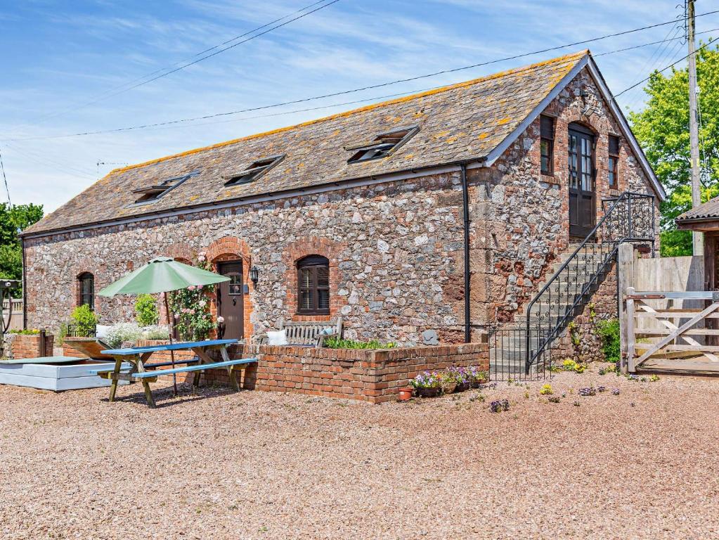 a stone building with a table and an umbrella at 3 Bed in Exeter KENCI in Clyst Saint Mary