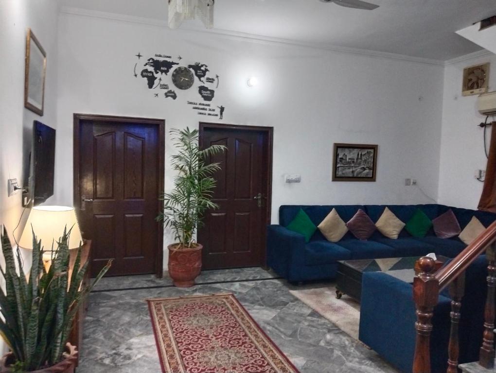 a living room with a blue couch and two doors at Homewood Suites Family Guest House & Apartments in Lahore
