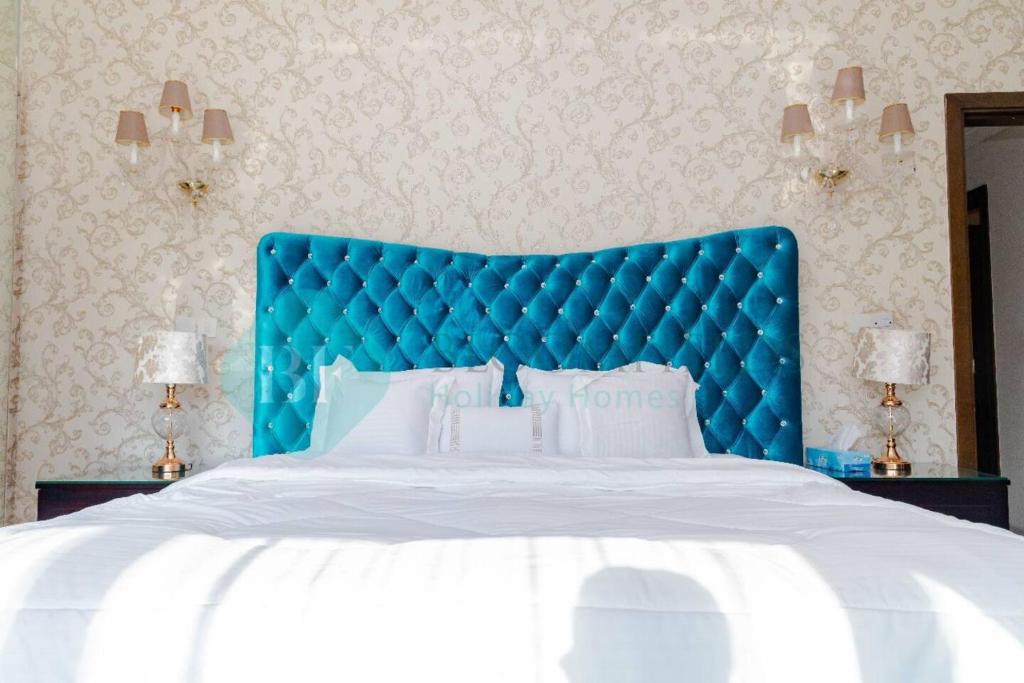 a bed with a blue headboard in a bedroom at Grandeur 3 Bedroom In Wave in Abu Dhabi