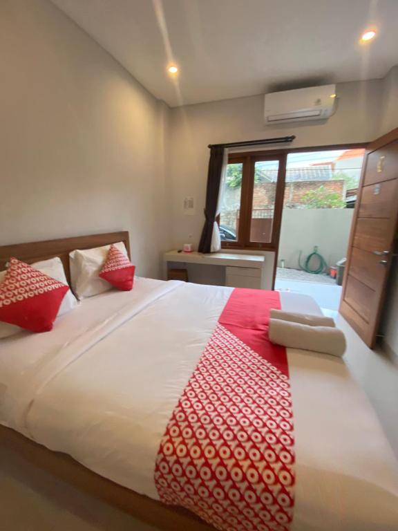 1 dormitorio con 1 cama con manta roja y blanca en Kencana residence by holistic group en Jimbaran