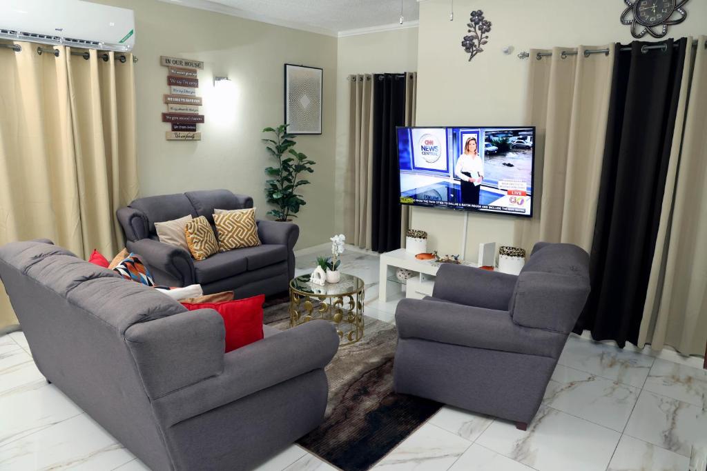 Spacious Luxury 3 Bed Rooms in Kingston في كينغستون: غرفة معيشة مع كرسيين وتلفزيون بشاشة مسطحة