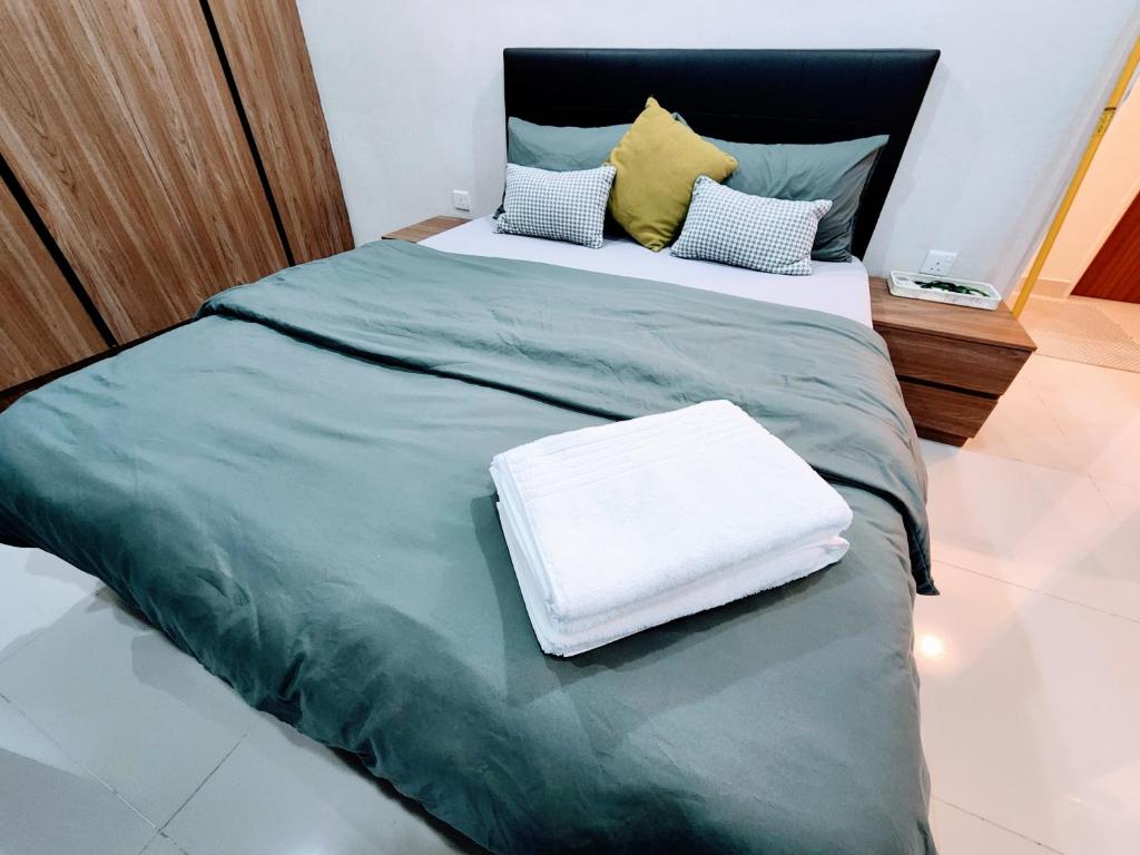 a large bed with a green blanket and pillows at Kozi Square Twin Room with free Wi-fi & Carpark in Kuching
