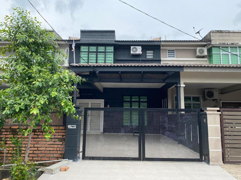 een huis met een zwarte poort ervoor bij Kuza Homes Batu Berendam in Melaka