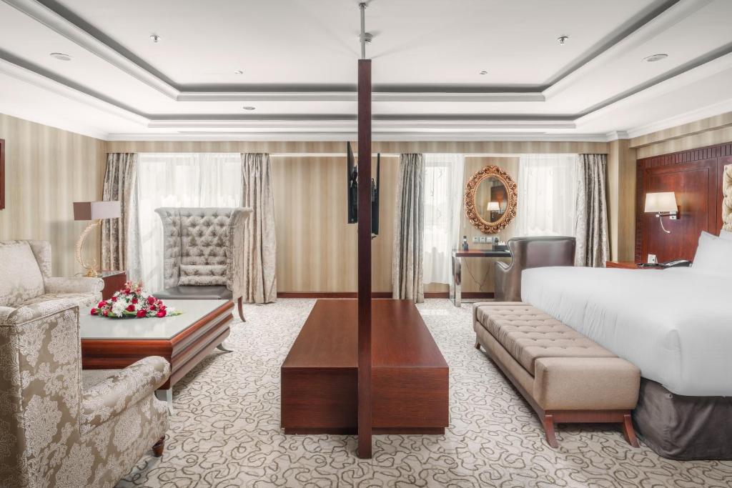メディナにあるAl Aqeeq Madinah Hotelのベッドとリビングルームが備わるホテルルームです。