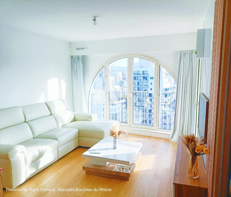 un salon avec un canapé blanc et une grande fenêtre dans l'établissement Appart Standing Free Parking Balcony Terrasse & Clim, à Marseille