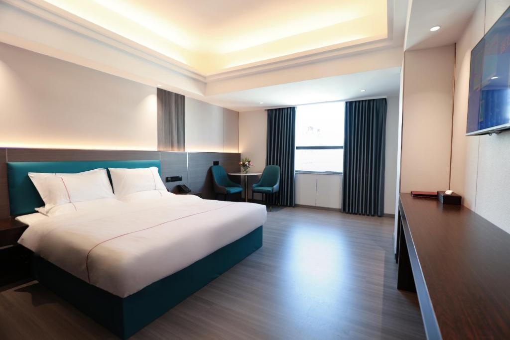 広州市にあるMei Gang Hotelのベッドとテーブルが備わるホテルルームです。