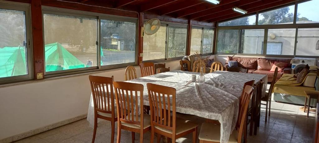 een eetkamer met een tafel, stoelen en ramen bij משפחתית בשובה 
