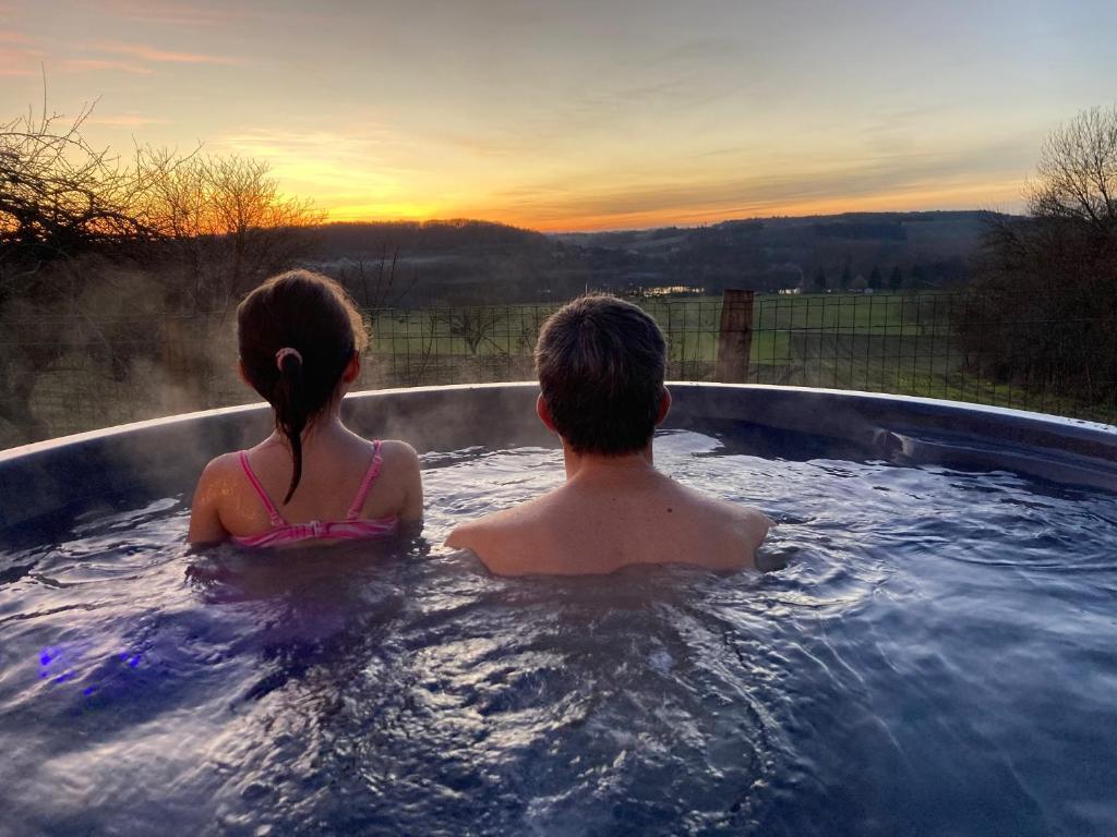 a man and a woman sitting in a hot tub at Spa nordique avec vue sur la campagne in Saint-Paul-Lizonne