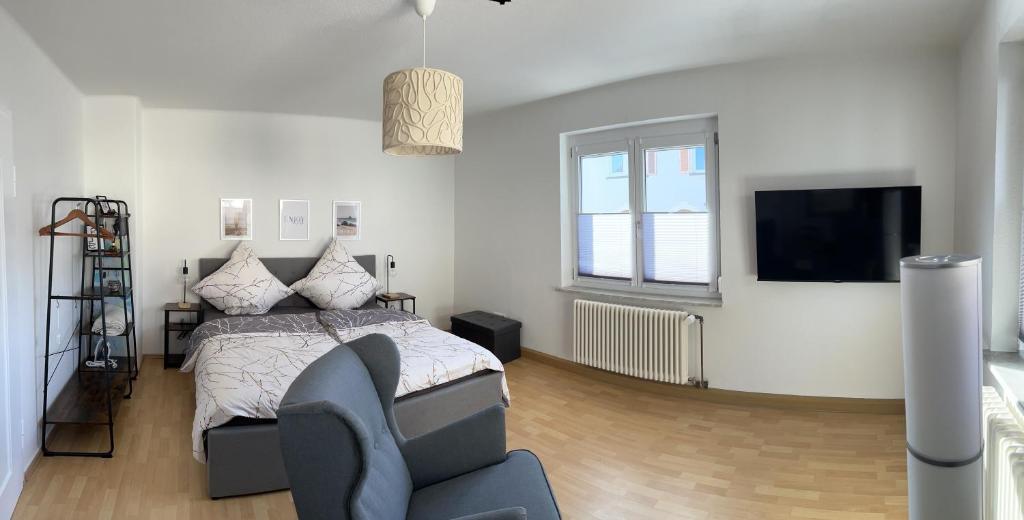 1 dormitorio con 1 cama, TV y silla en Feel like Home 2, en Biberach an der Riß