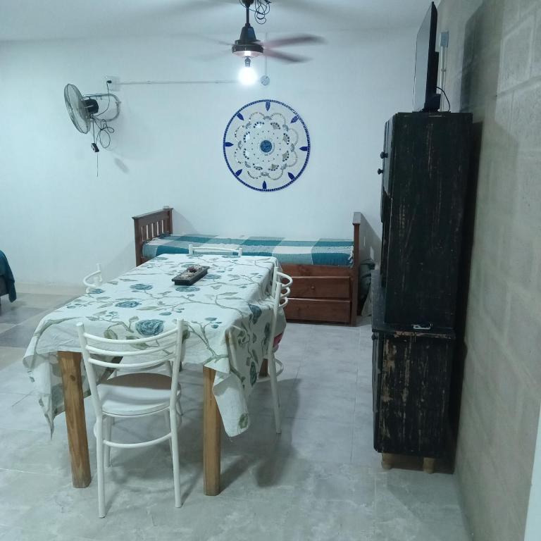 a room with a table and a bed and a clock at Acogedor y familiar departamento c est in Santiago del Estero