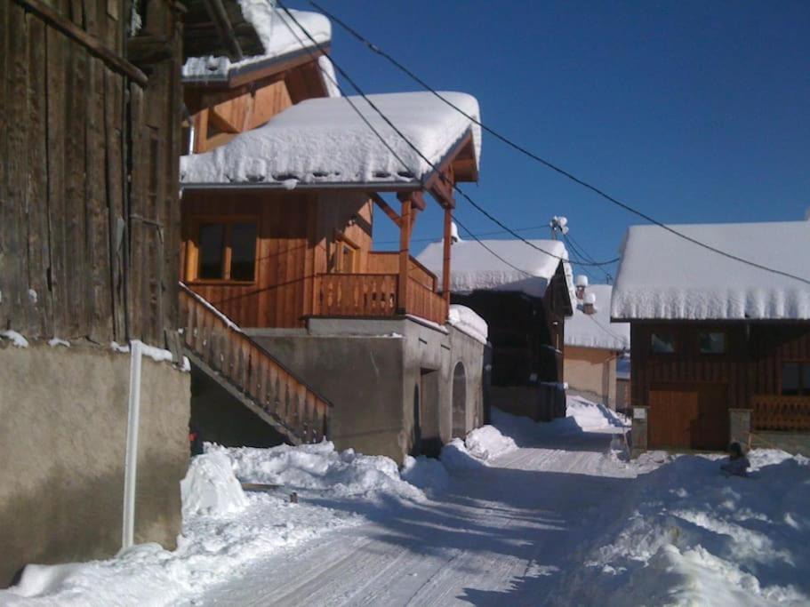 ein Haus mit Schnee auf dem Boden neben einem Gebäude in der Unterkunft Chalet montagne Savoie Domaine Skiable Valmorel in La Lechere