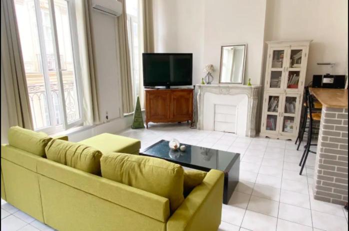 ein Wohnzimmer mit einem gelben Sofa und einem TV in der Unterkunft Appartement Idéal en centre ville in Montpellier