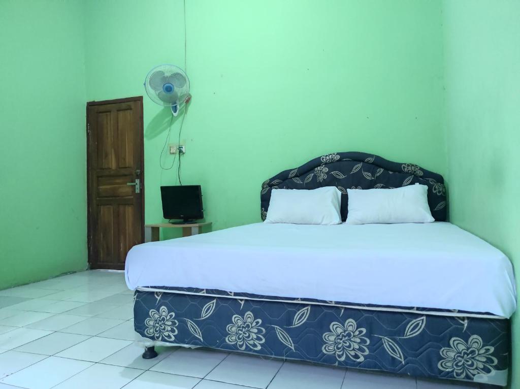 1 dormitorio con 1 cama y ventilador en OYO 93411 Syariah Hotel Tomborang en Karema
