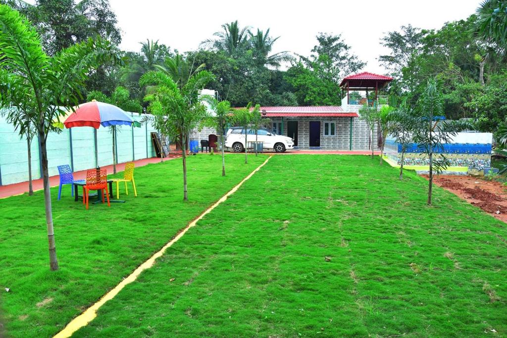 um quintal com cadeiras e um guarda-sol e uma casa em Re leaf Resort em Auroville