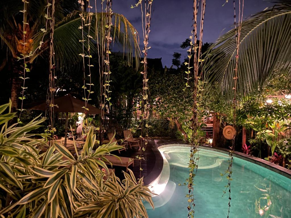 una piscina en un complejo por la noche en Umakayu Joglo Villa Canggu - Boutique Hotel en Canggu