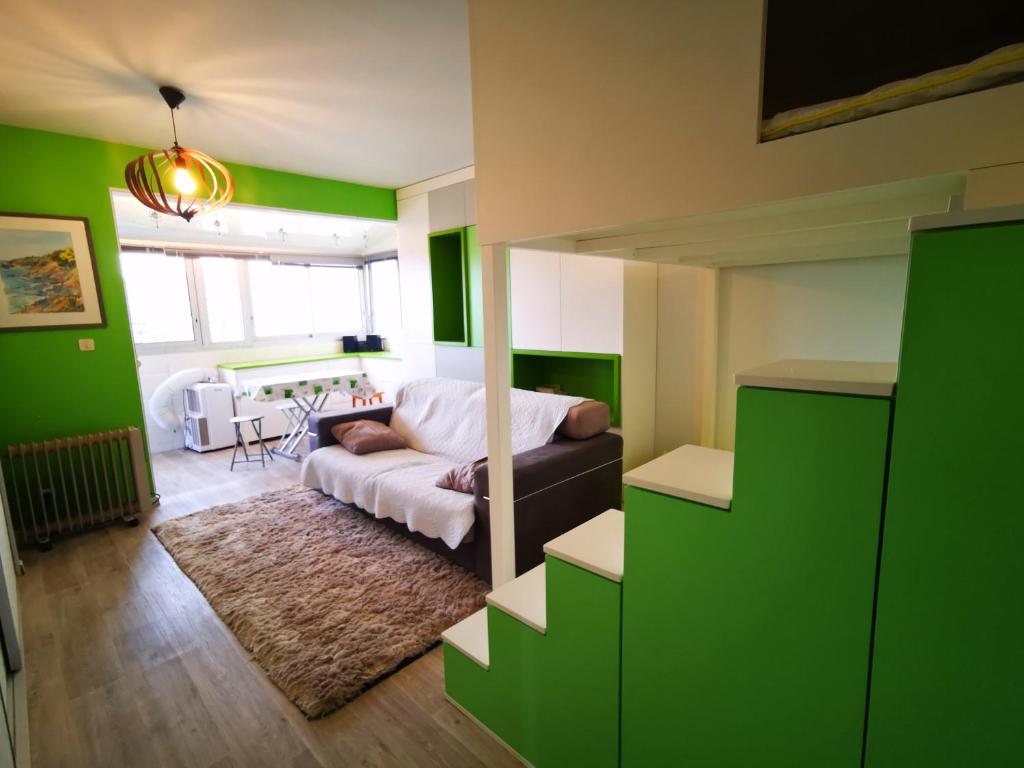 - un salon avec des murs verts et un canapé dans l'établissement Le petit Bois en bord de mer - accès animations, commerce et plage, à Argelès-sur-Mer