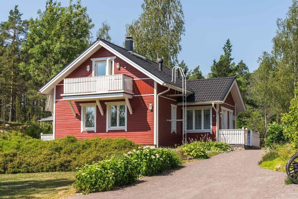 a red house with a balcony and a driveway at Cottage Charm - Cozy Getaway in the Archipelago in Naantali