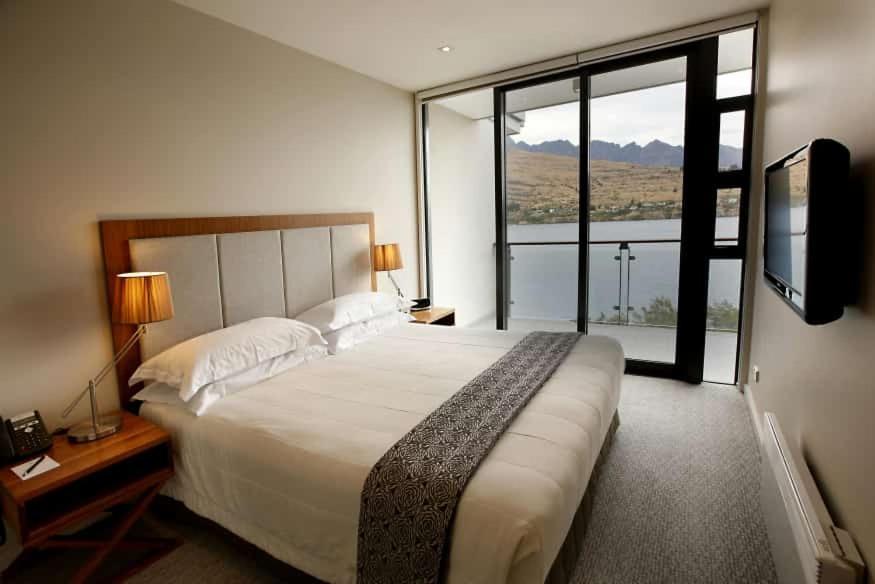 um quarto com uma cama grande e uma janela grande em KARIBA SUN BEACH APARTMENT em Rutsiro