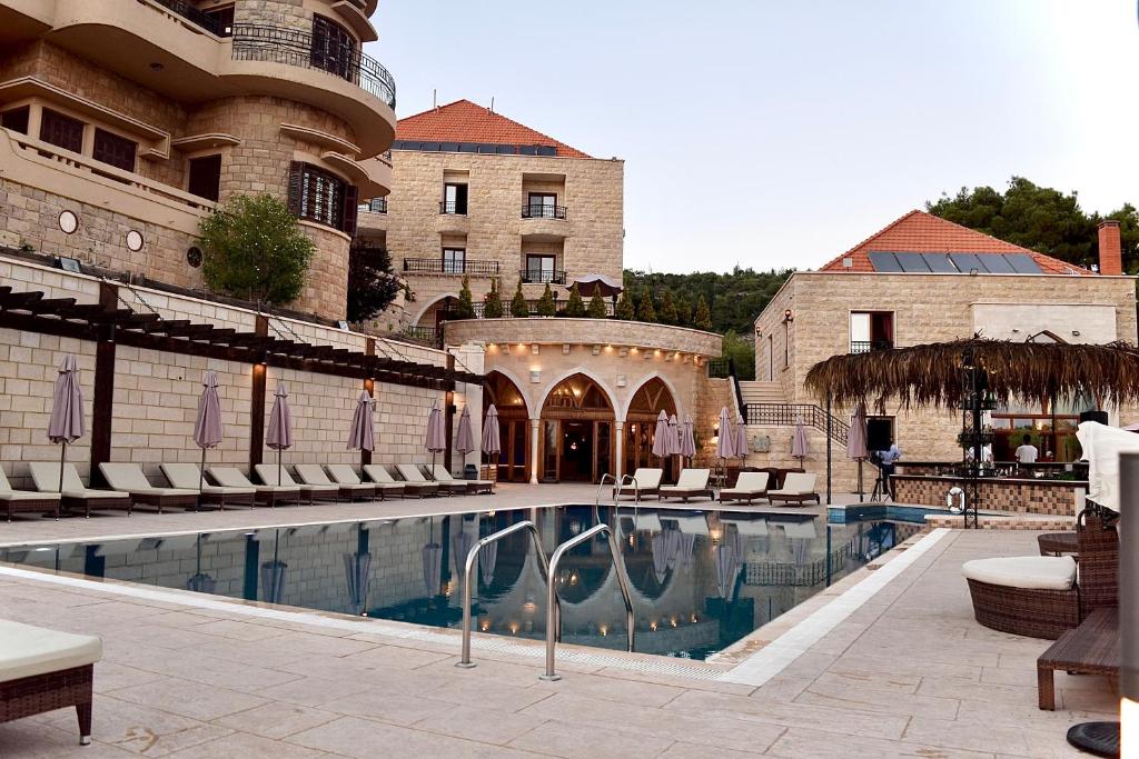 un hotel con piscina con sillas y un edificio en L'auberge des Emirs, en Dayr al Qamar