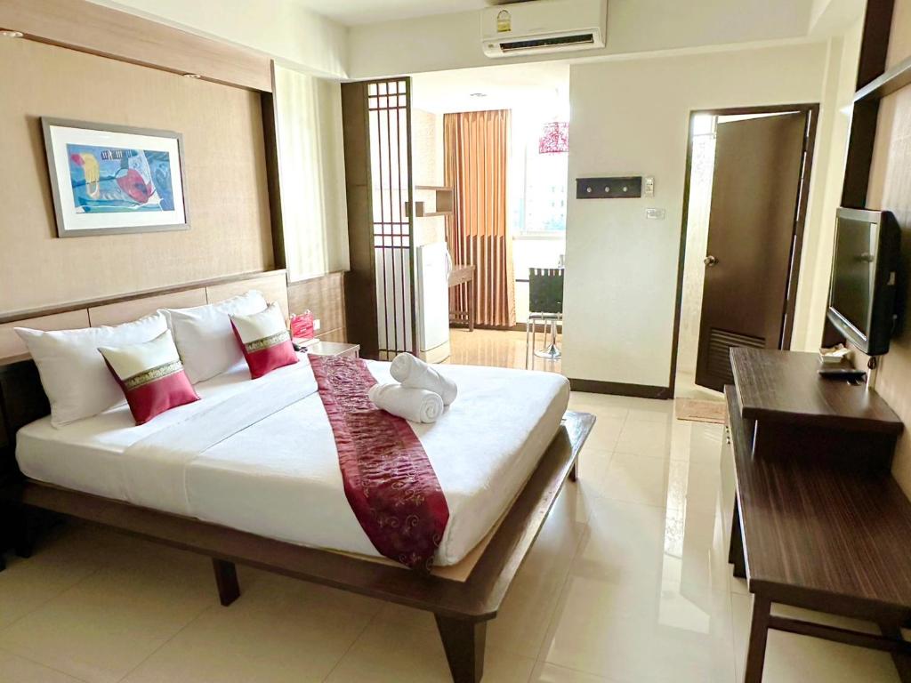 A bright double room with a large bed, television, desk, and balcony doorway.