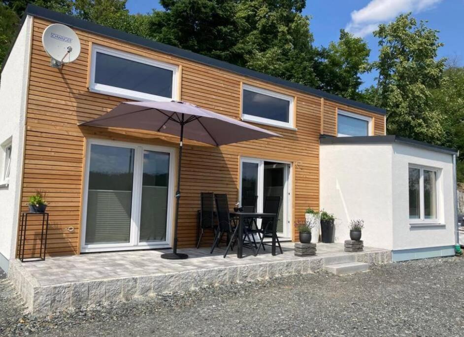 a small house with an umbrella and a table at Tinyhouse Wald(t)raum in Wilhelmsthal