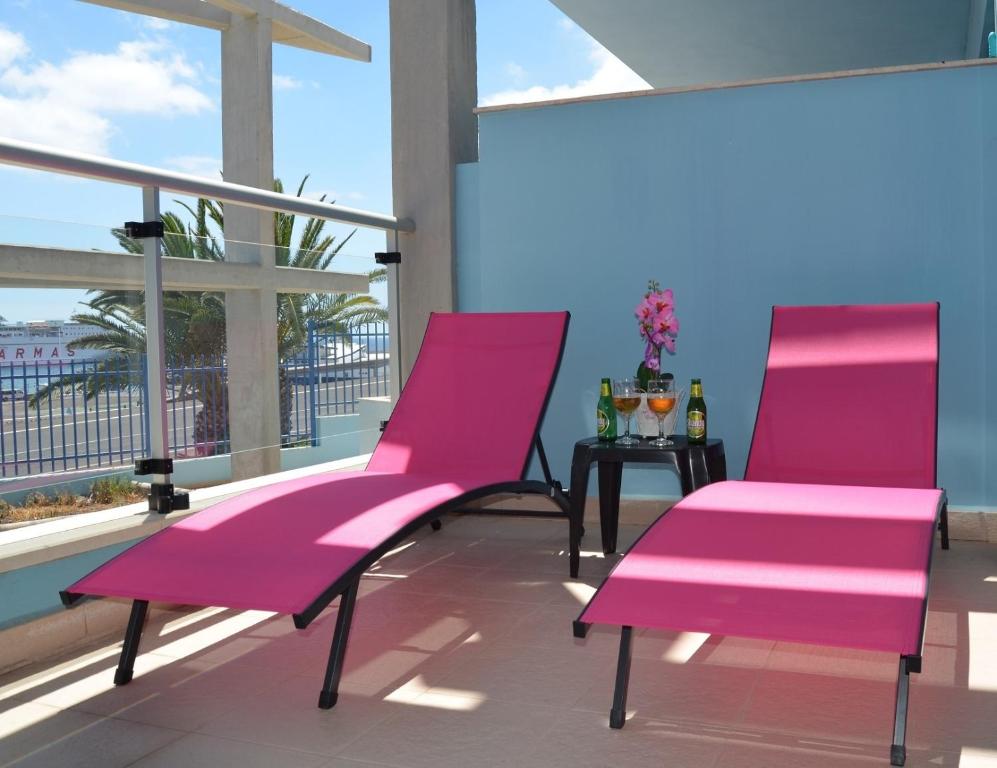 2 sillas rosas en un balcón con mesa en Residencial Jandía Marina, en Morro del Jable