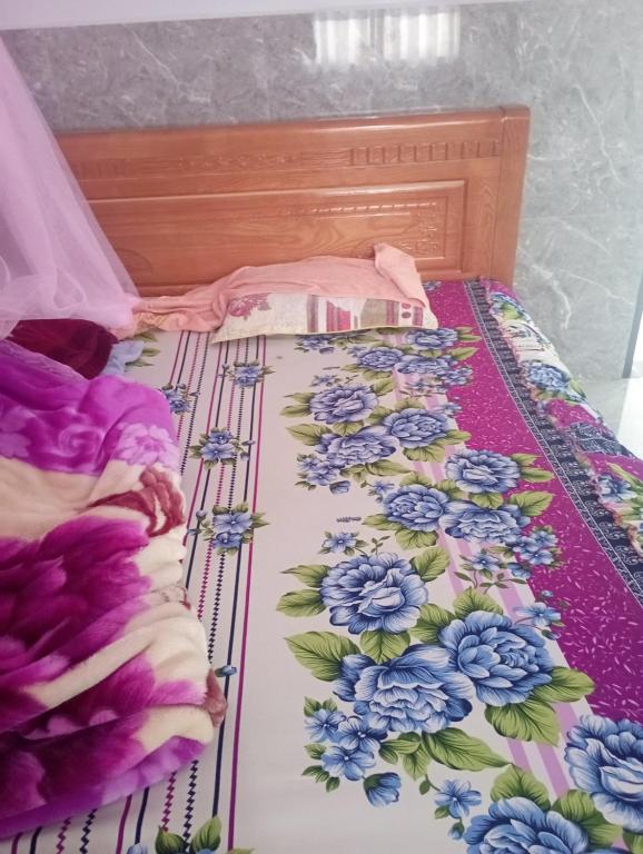 a bed with blue flowers on it at Thi Thao Homestay in Di Linh