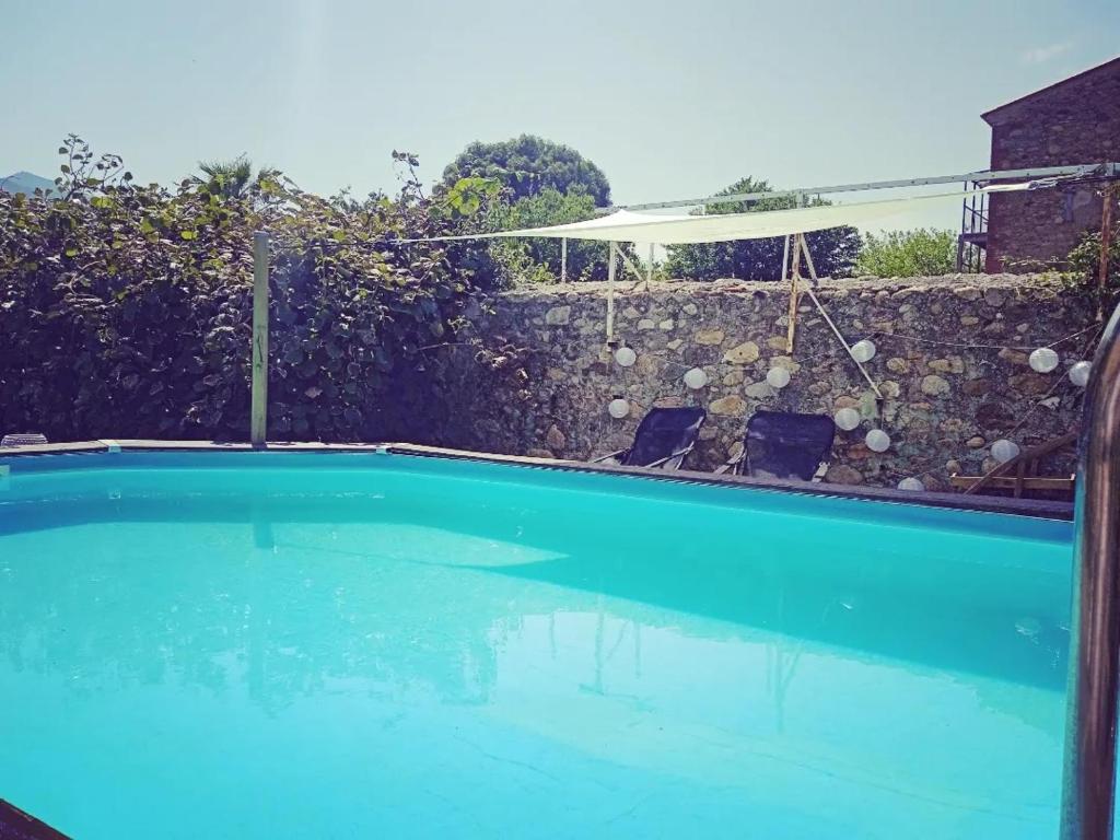 a blue swimming pool with a fence and an umbrella at Grande maison coeur de village piscine jacuzzi in Maureillas
