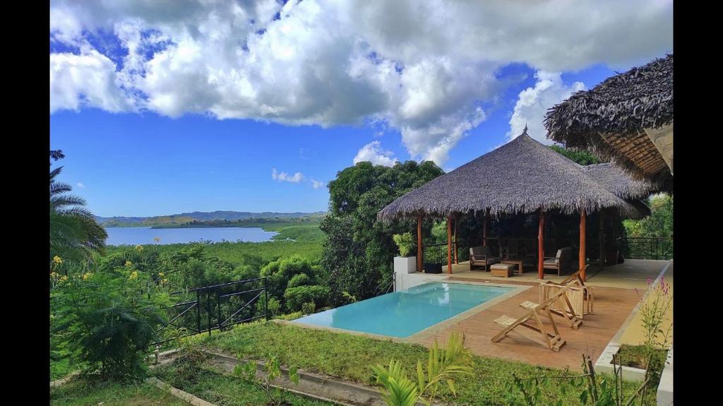 a villa with a swimming pool and a thatch roof at Villa Agay in Nosy Be