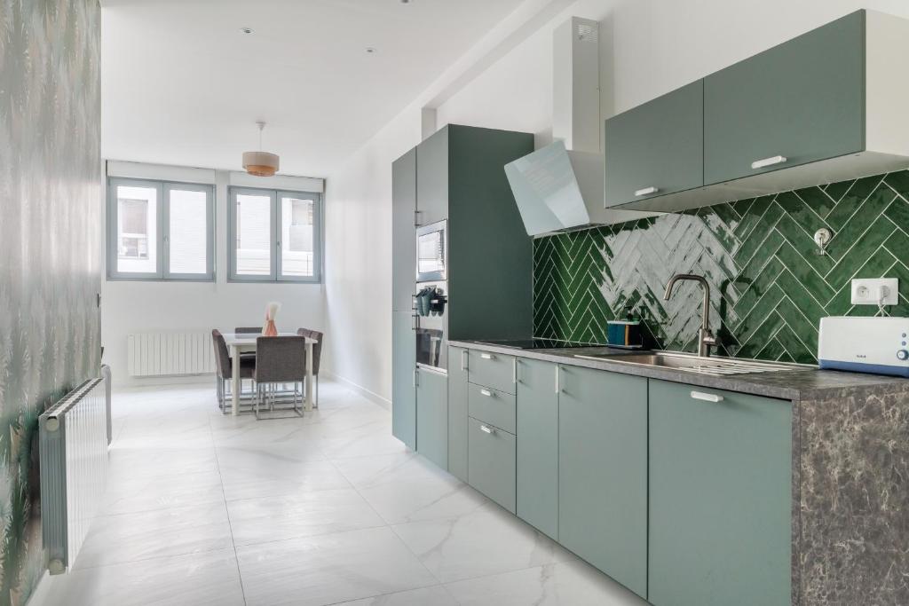 a kitchen with green and white cabinets and a table at Spacious apartments for 6 people #3 in Asnières-sur-Seine