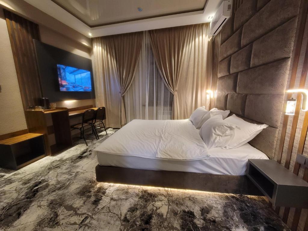 1 dormitorio con 1 cama blanca grande y escritorio en Homy House Hotel en Tashkent