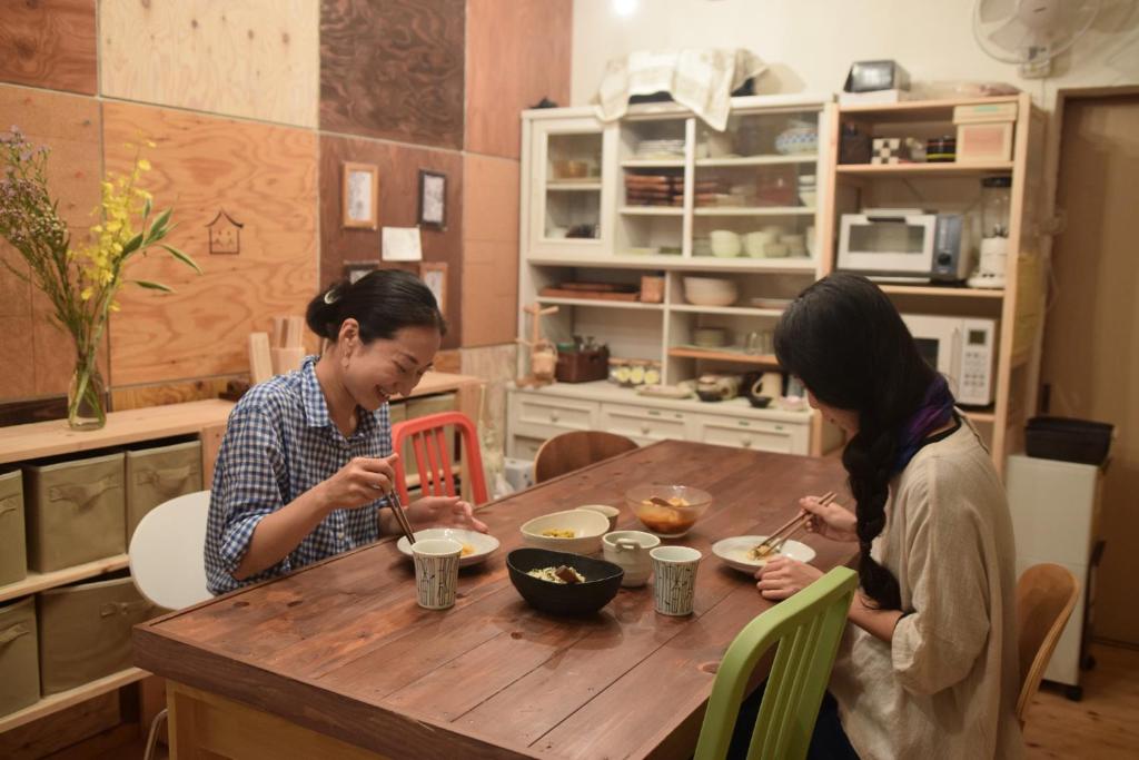 two women sitting at a wooden table eating food at シェアハウスまちやど-machiyado home stay- in Gujo