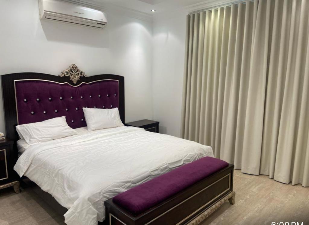 1 dormitorio con 1 cama grande y cabecero púrpura en Alwaha-Appartement en Riad