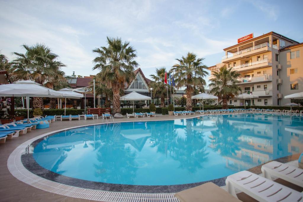 una gran piscina con sillas y sombrillas en un hotel en Godija Hotel & Suites, en Velipojë