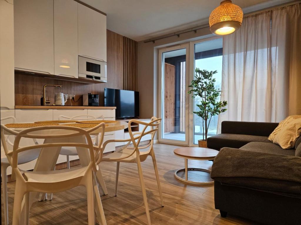 a kitchen and living room with a table and chairs at Apartament Laguna Beskidów - Zarzecze in Zarzecze