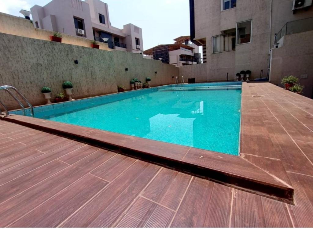 a large swimming pool with a wooden floor and buildings at HAZYHILLS Staycation in Igatpuri
