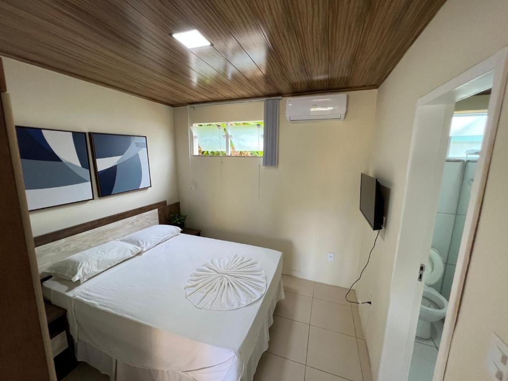 um pequeno quarto com uma cama e uma televisão em Apartamento em Itaparica em Bôca do Rio