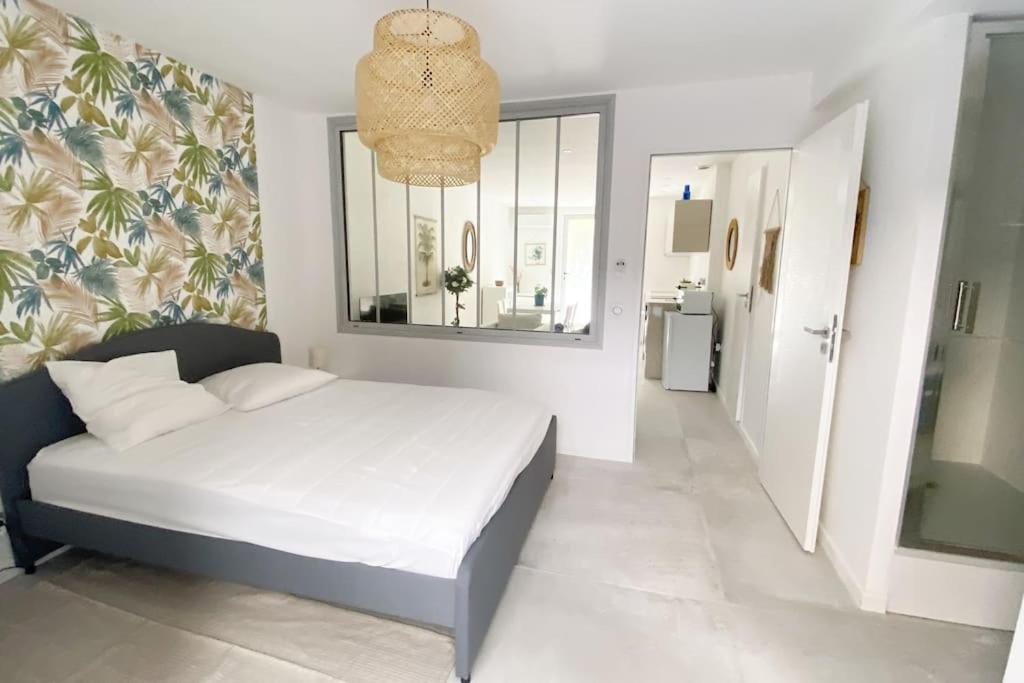 - une chambre avec un lit blanc et un lustre dans l'établissement Apt T2 neuf, terrasse, centre ville, 8min Comédie, à Montpellier