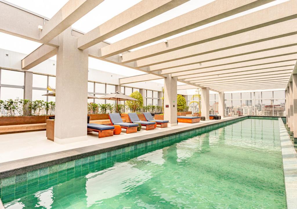 une piscine intérieure avec des chaises longues et un bâtiment dans l'établissement Charlie Wide Pinheiros, à São Paulo