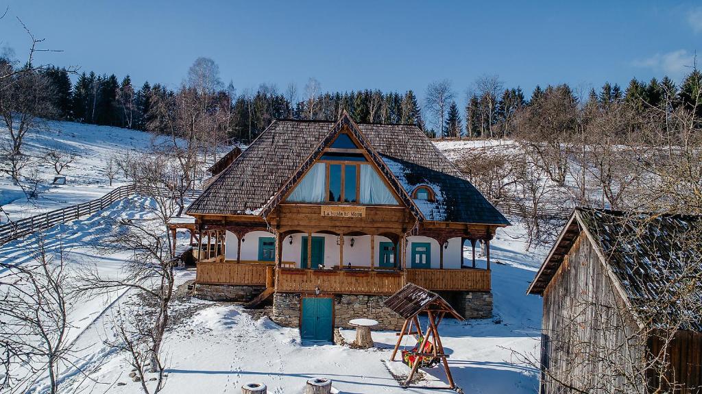 een houten huis in de sneeuw met sneeuw bij La bujda lu mosu in Borşa