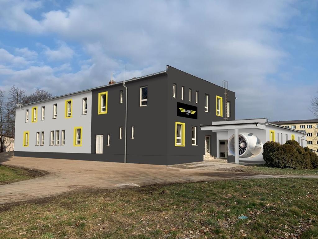 un gran edificio negro con ventanas amarillas junto a un patio en Hotel Hangar, en Mošnov