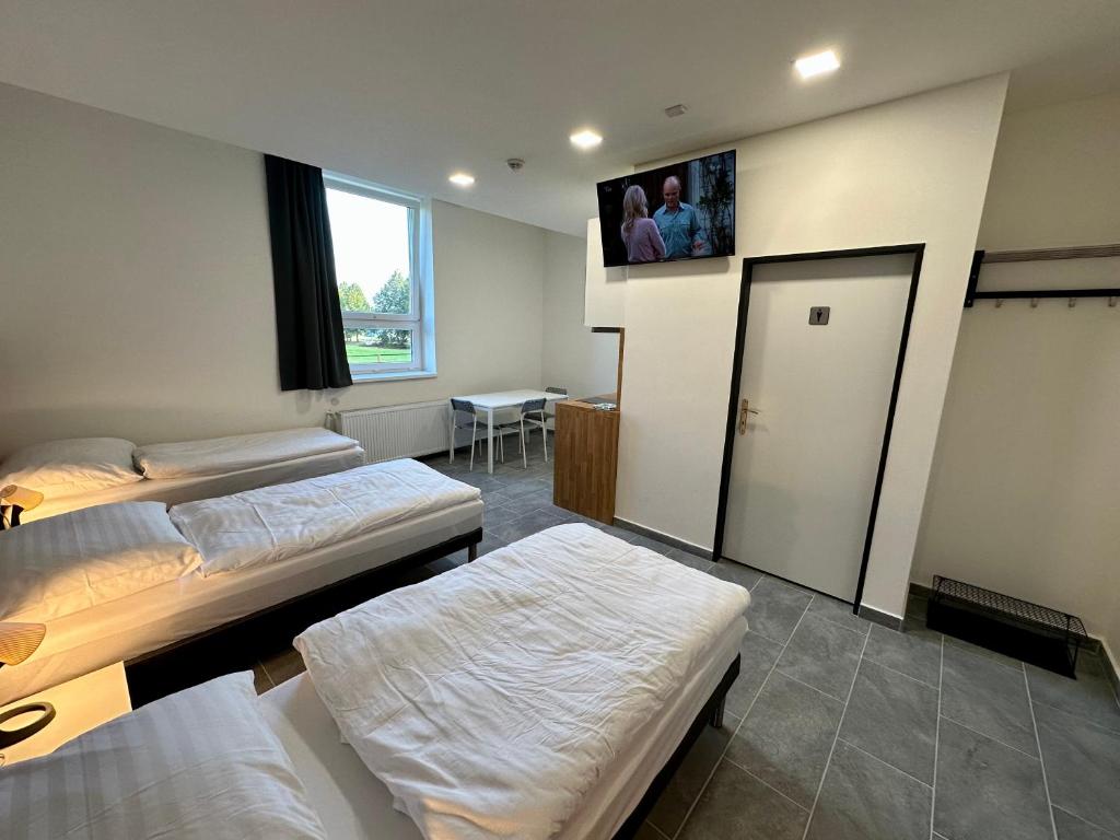 a room with two beds and a tv on the wall at Hotel Hangar in Mošnov