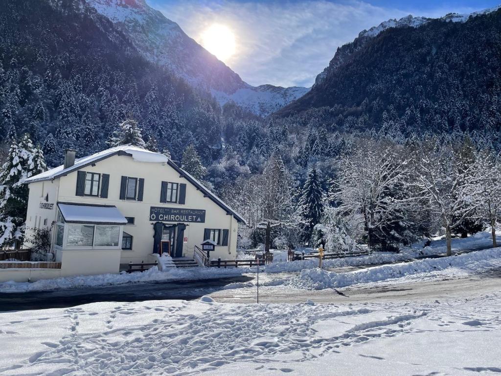 un edificio en la nieve frente a una montaña en Hotel O Chiroulet, en Bagnères-de-Bigorre