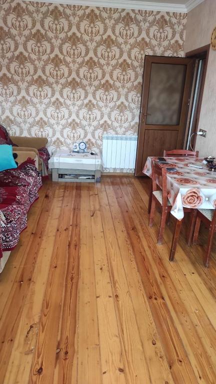 un soggiorno con tavolo e pavimento in legno di AYXAN HOSTEL a Ganja