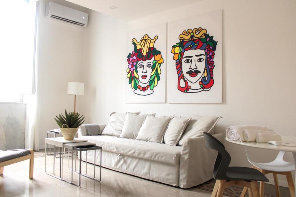 dos pinturas de payasos en la pared en una sala de estar en Palazzo Caltagirone Suite en Palermo