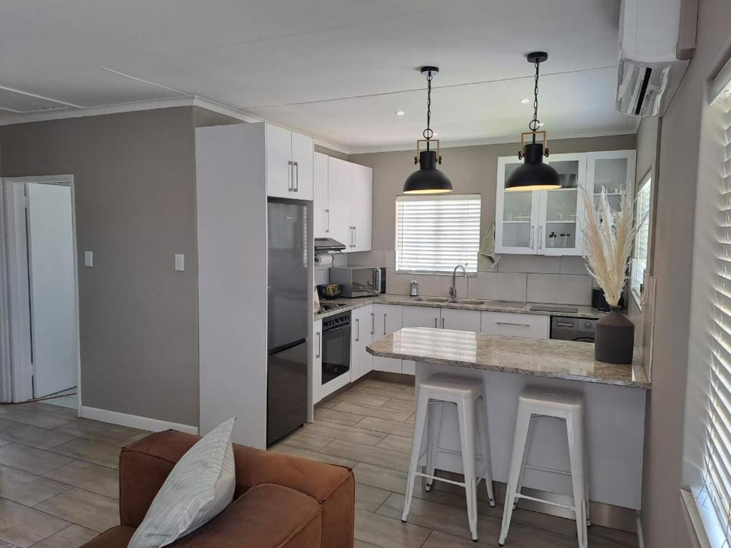 a kitchen with white cabinets and a table and a couch at The Galton Villa in Windhoek