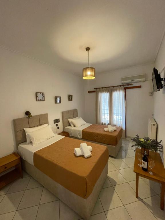 um quarto de hotel com duas camas e uma televisão em Oscar Hotel Lefkada em Nydri