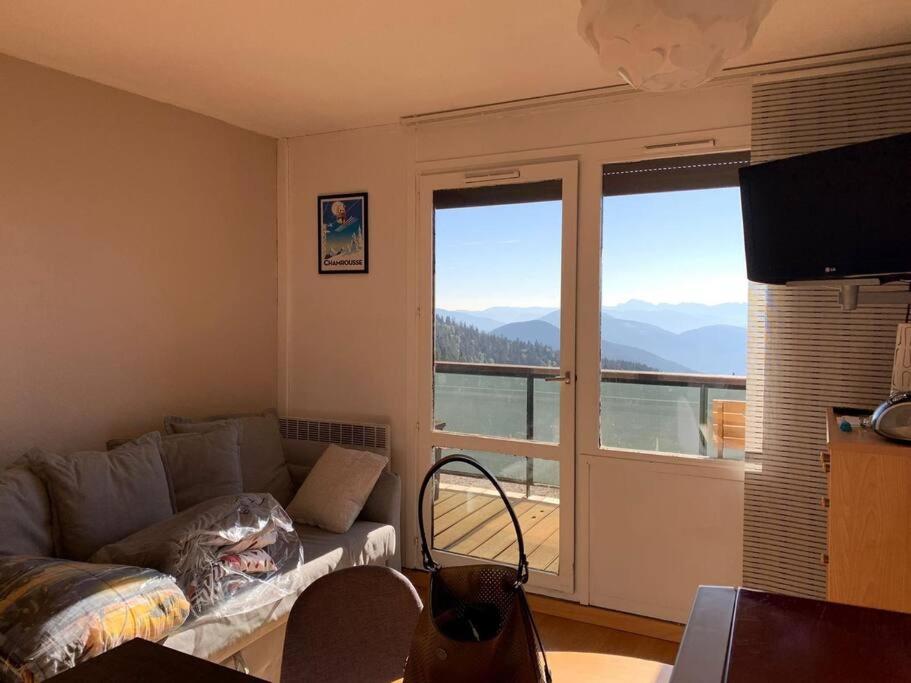 a living room with a couch and a large window at 4 personnes in Chamrousse