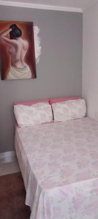 a bed in a room with a painting on the wall at Apartamento térreo, 2 quartos, 300m da praia de Atalaia, Aracaju in Aracaju