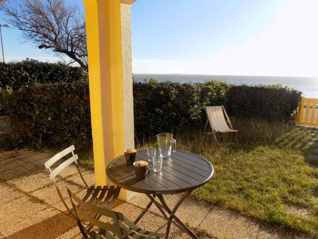 una mesa y sillas en un patio con vistas al océano en Saint Palais sur Mer - APPARTEMENT FACE MER sur la corniche de NAUZAN, en Saint-Palais-sur-Mer